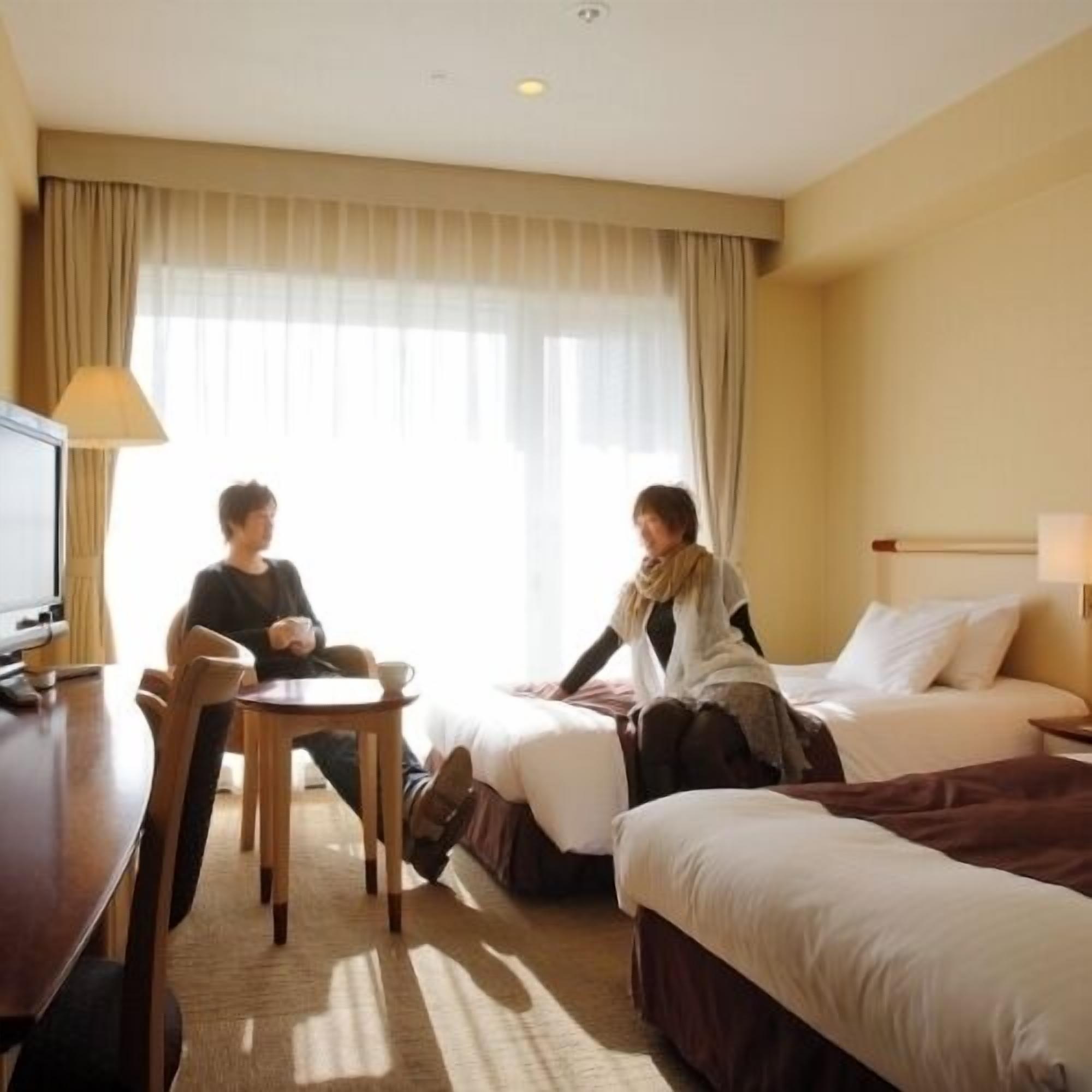 A hotel room with a bed, a desk, a chair, and a television.