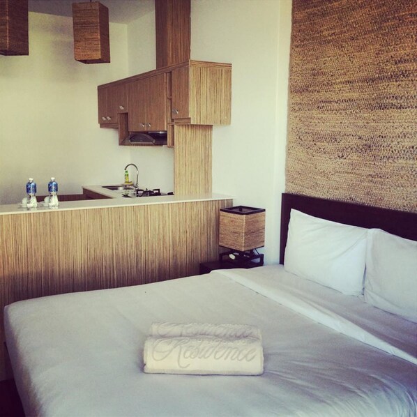 A hotel room with a bed, a wooden vanity with a sink, and a woven wall panel. - Surf4You Residence (Mui Ne)