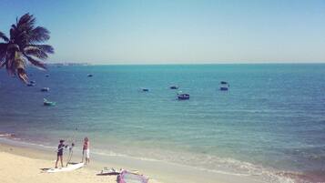 A beach with a clear sky, calm sea, and a few boats.