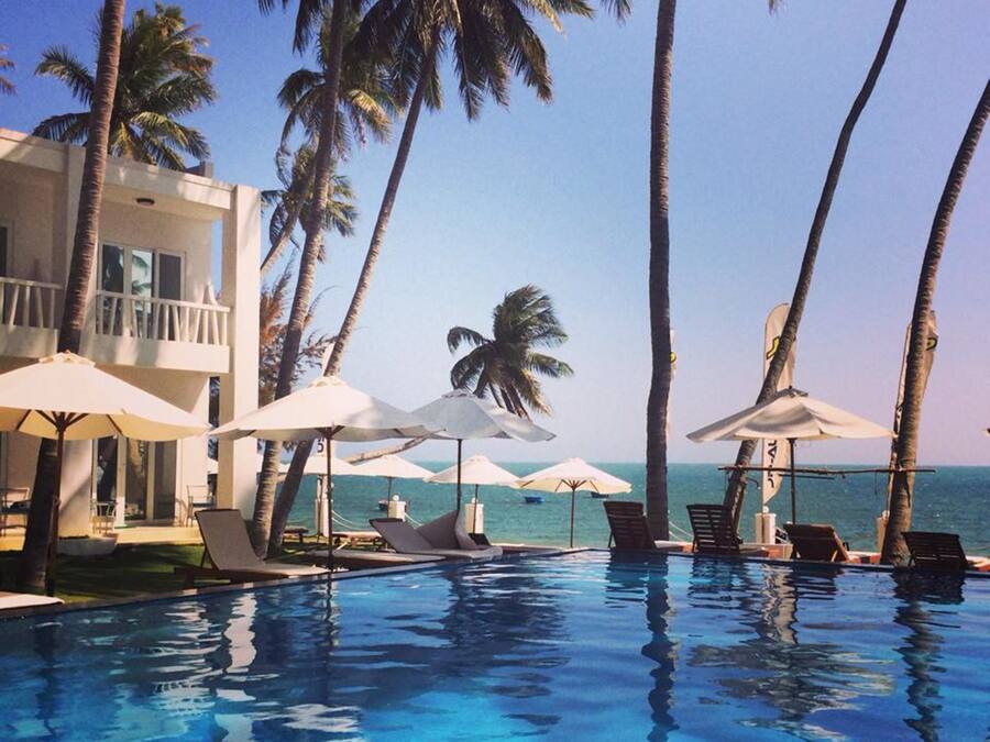 Una piscina al aire libre, sombrillas, sillones reclinables de piscina