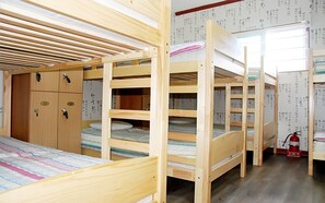 A dormitory room with bunk beds, wooden lockers, and a fire extinguisher. - Amuse Guest House - Hostel (Seoul)
