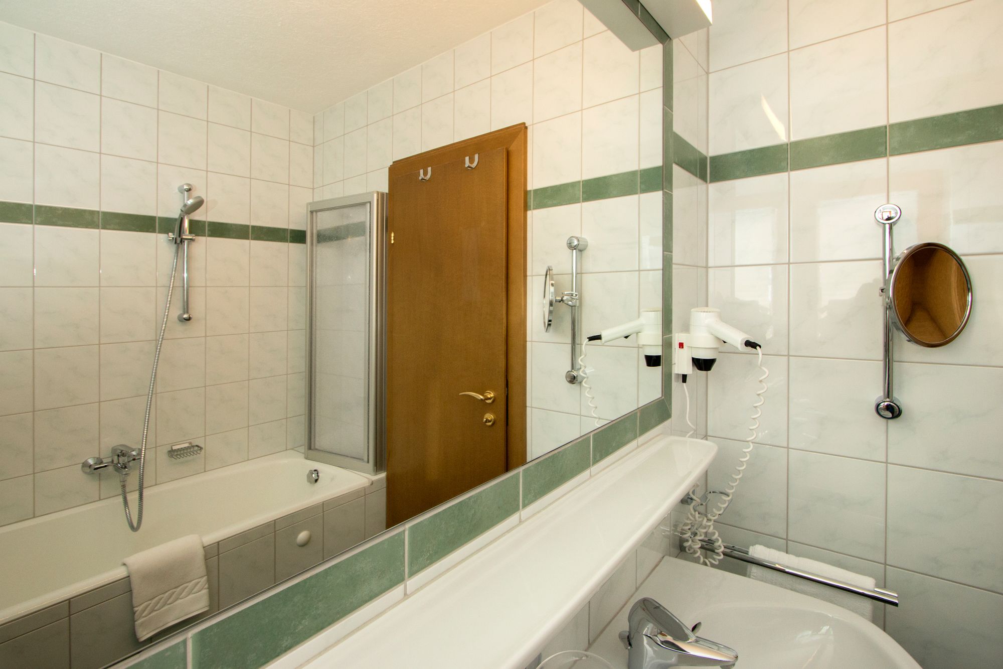Une salle de bain équipée d’une baignoire, d’une douche, d’un porte-serviettes et d’un miroir.