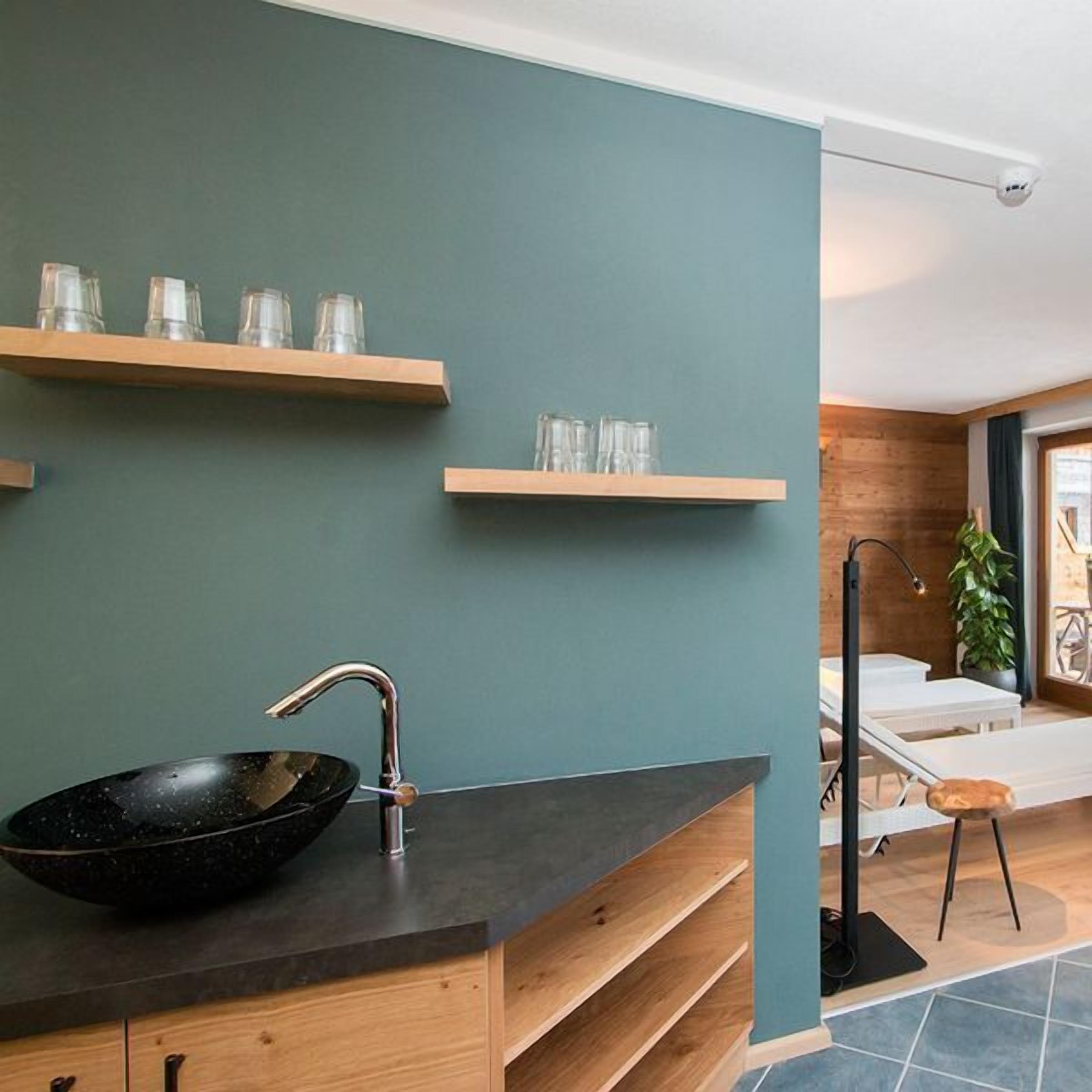 Ein modernes Badezimmer mit einem schwarzen Waschbecken, Holzregalen und einem großen Spiegel.