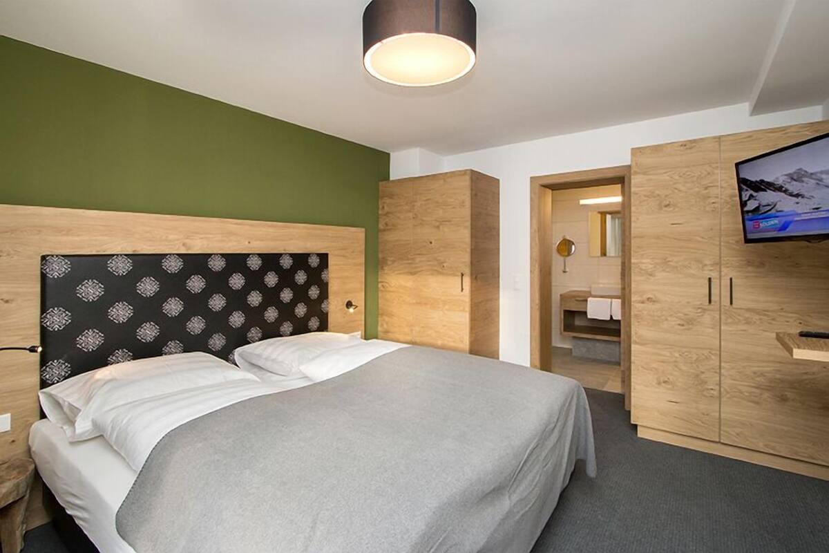 Een moderne hotelkamer met een bed, een houten garderobe en een televisie.