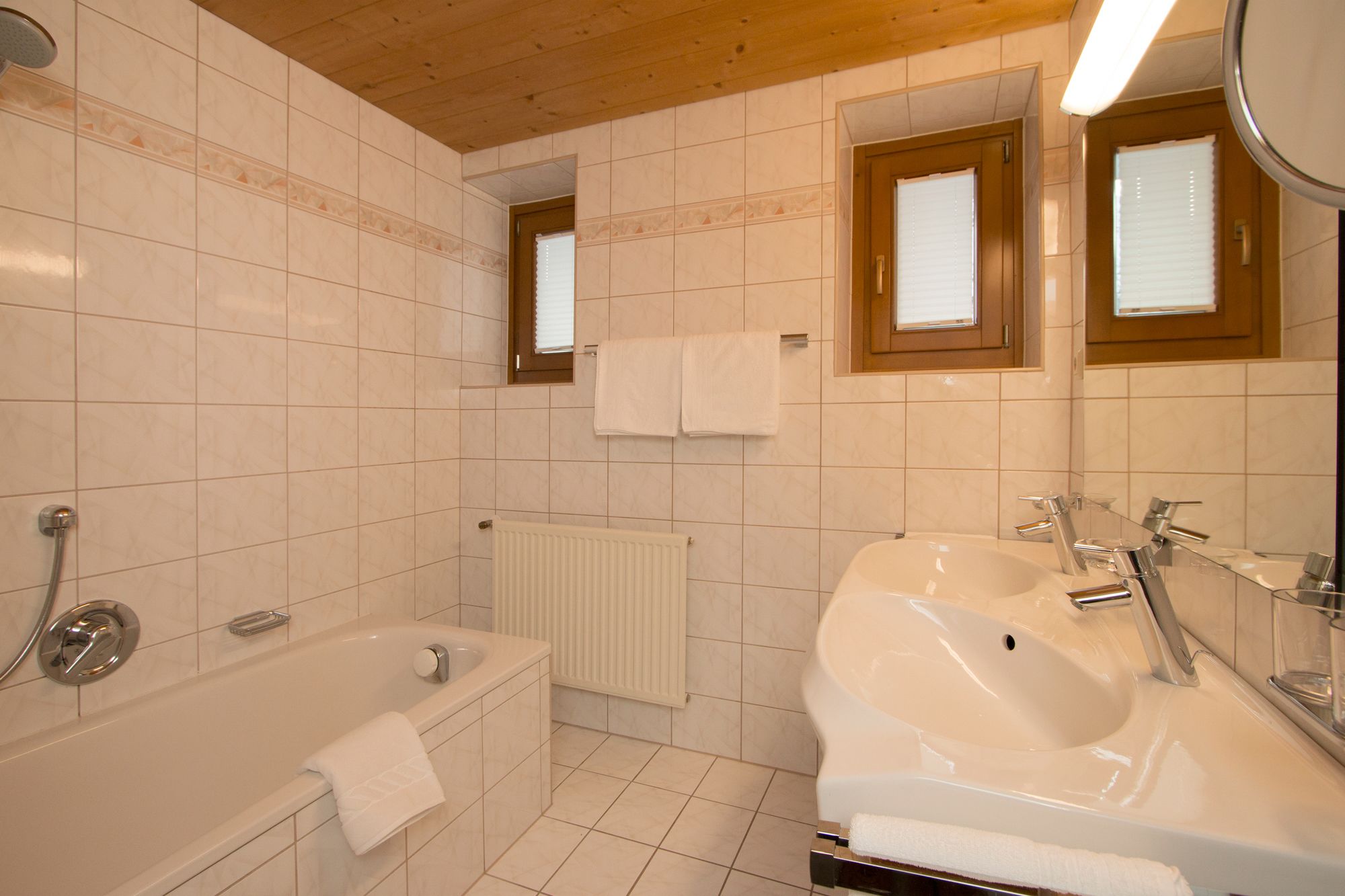 A modern bathroom with a bathtub, a sink, and two mirrors.