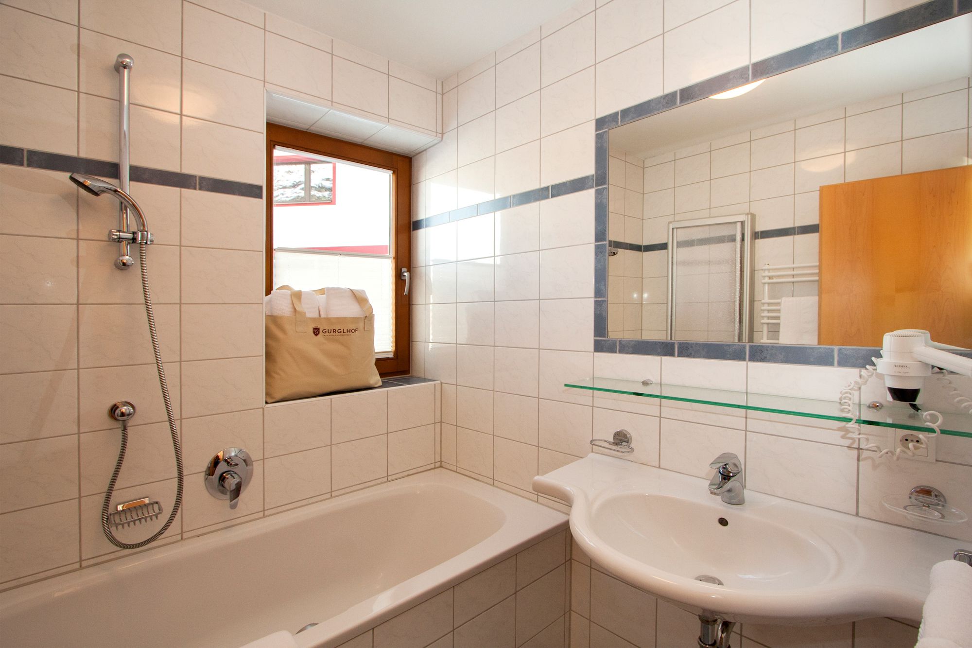 Un bany amb banyera, un lavabo, un mirall i una finestra.