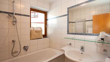 Un baño con bañera, lavamanos, espejo y ventana.