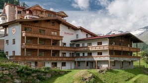 A multi-story building with a sign reading "Gurglhof" in a mountainous area with green hills and a clear sky. - Apartmenthaus Gurglhof (Soelden)