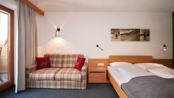 Una habitació d'hotel amb un llit, un sofà, una tauleta de nit i una làmpada penjada a la paret.
