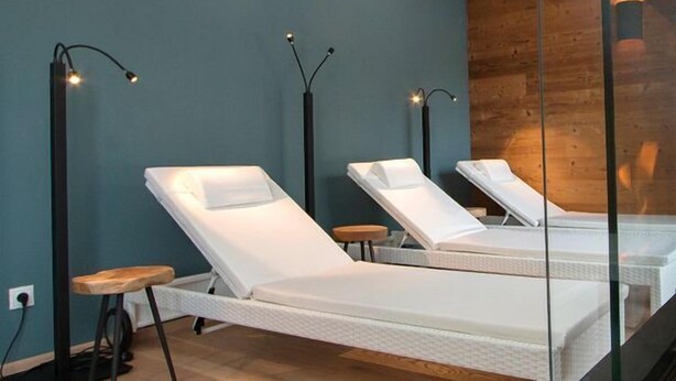 A modern spa room with two white massage tables, wooden flooring, and tall floor lamps. - Apartmenthaus Gurglhof (Soelden)