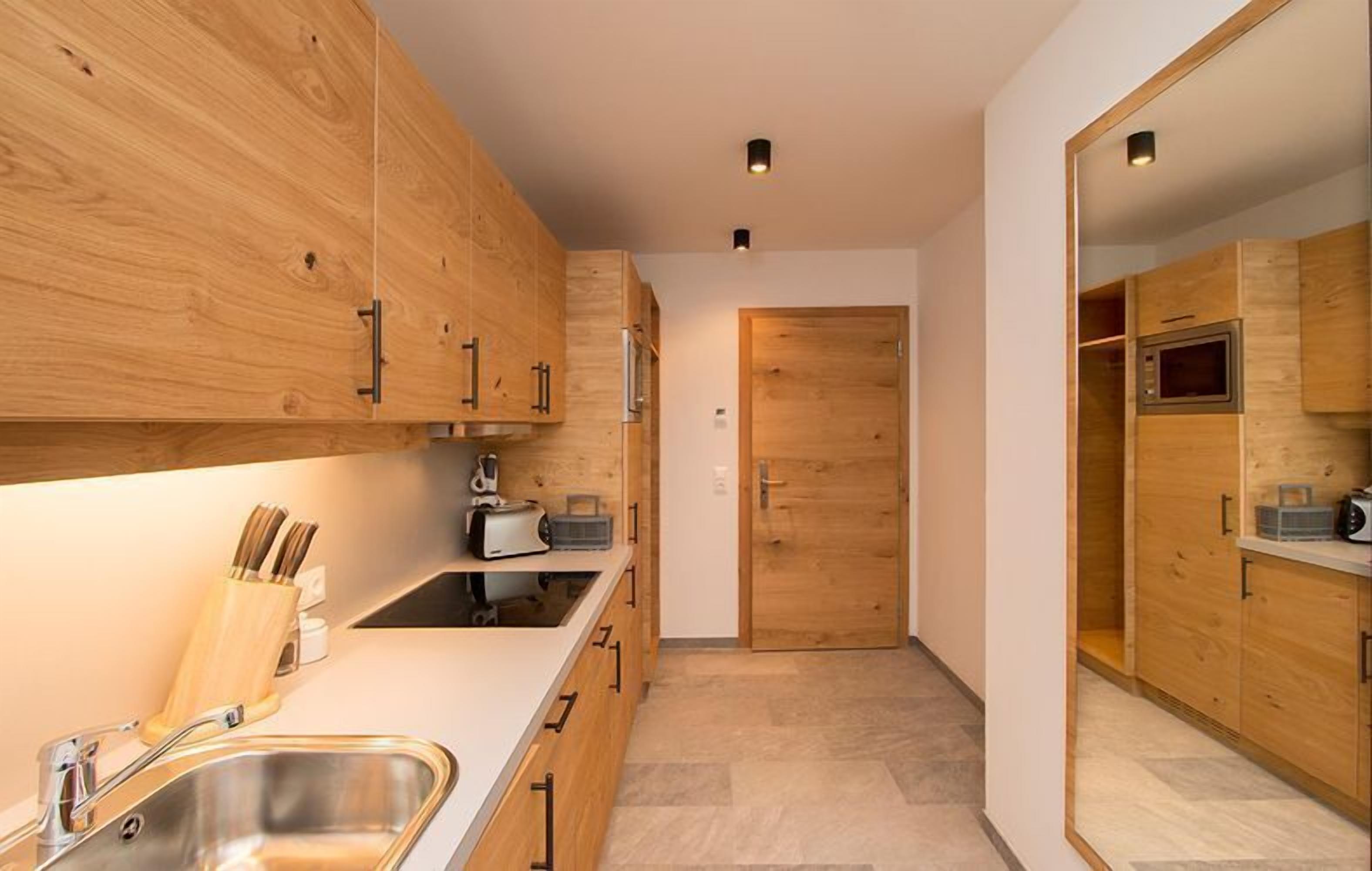 A modern kitchen with wooden cabinets, a stainless steel sink, and a built-in oven.
