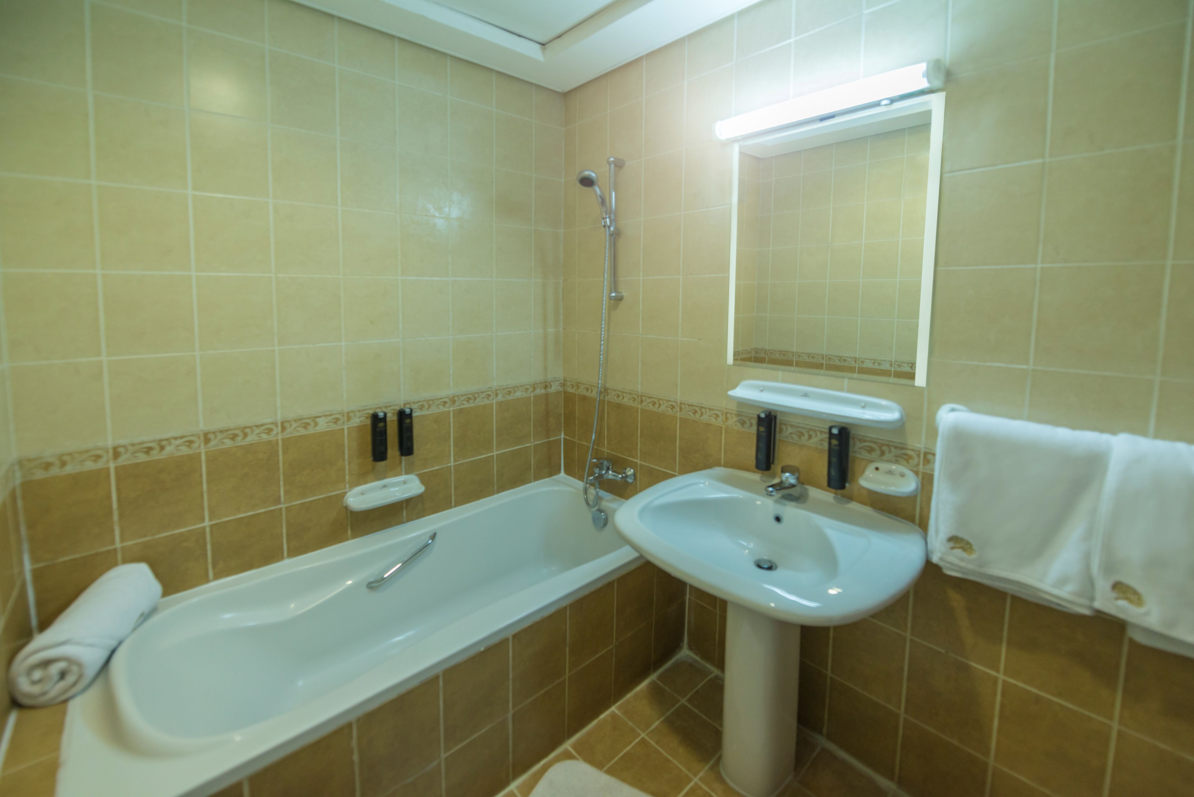 A bathroom with a bathtub, a sink, and a mirror.