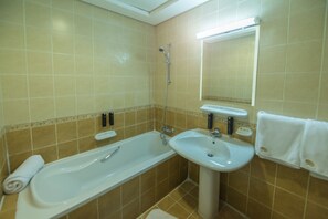 Un baño con bañera, lavamanos y espejo.