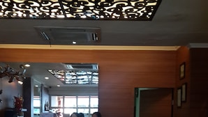 A reception area with a modern ceiling design, a reception desk, and a view of the interior space. - Hotel California (Jakarta)