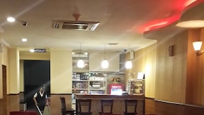 A restaurant with red upholstered booths, a bar area, and a visible toilet sign. - Hotel California (Jakarta)