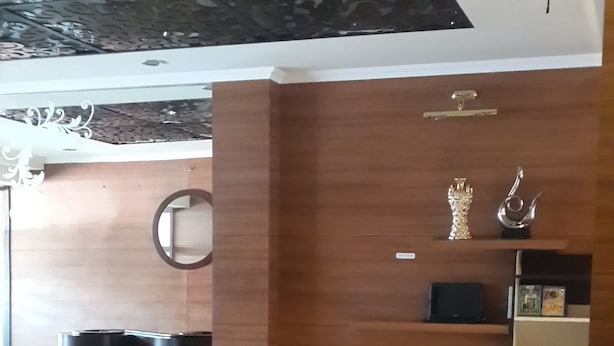 A modern interior with a wooden wall, a red sofa, a small trash bin, and a staircase. - Hotel California (Jakarta)