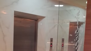 A modern elevator with digital displays, a marble wall, and a glass door. - Hotel California (Jakarta)