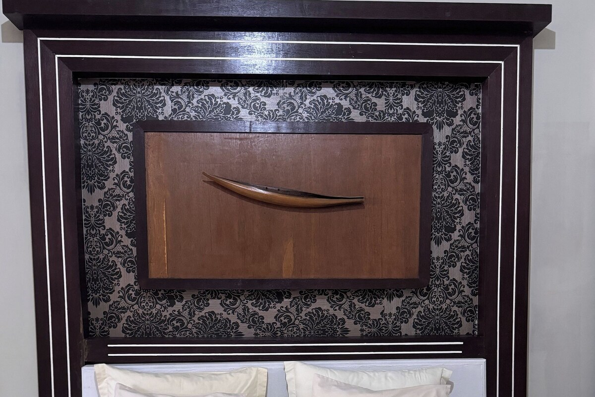 Una cama bien hecha con dos almohadas y una toalla doblada.