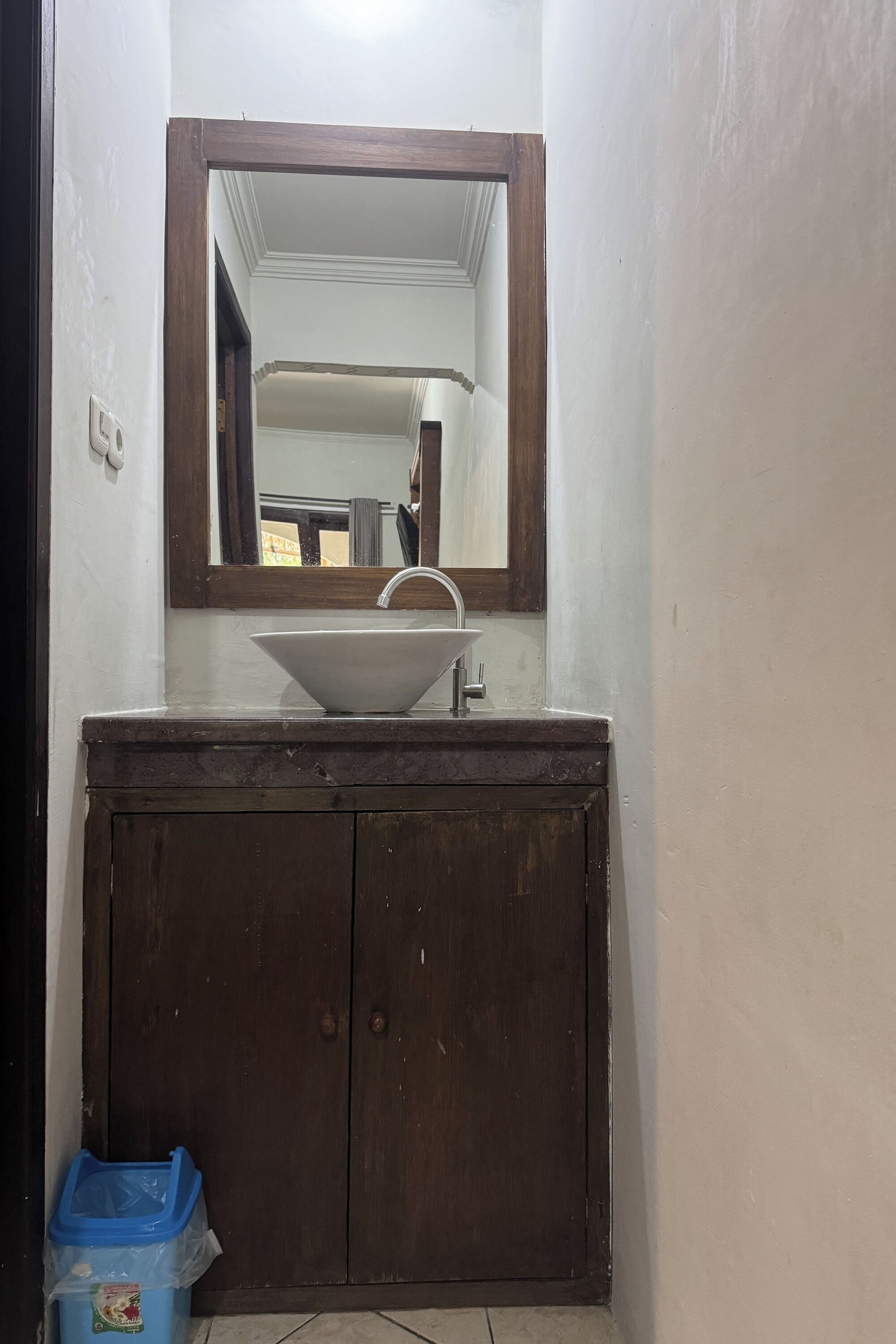 Un baño con un lavamanos blanco, tocador de madera y un espejo encima.