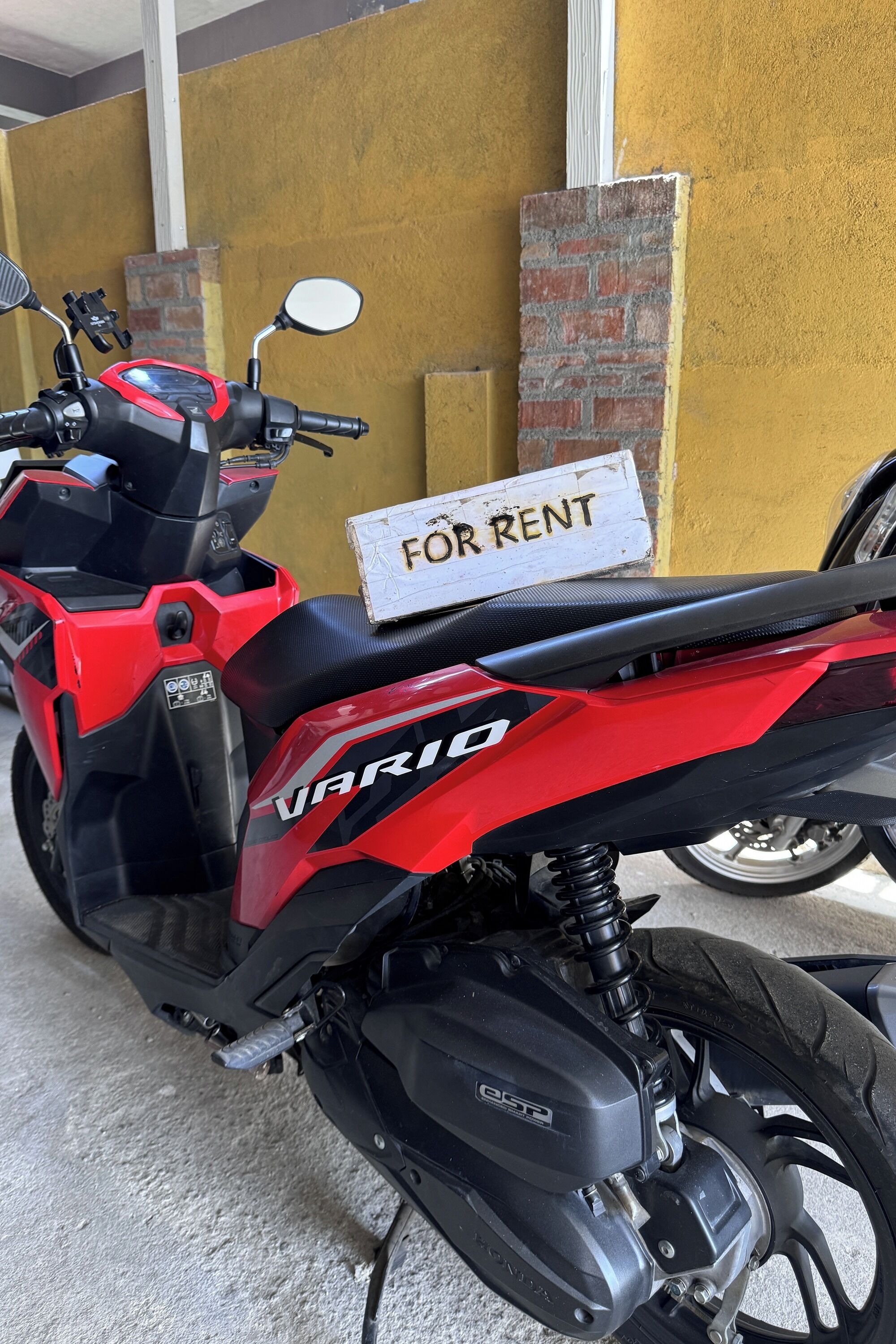 A red and black scooter with a "FOR RENT" sign.