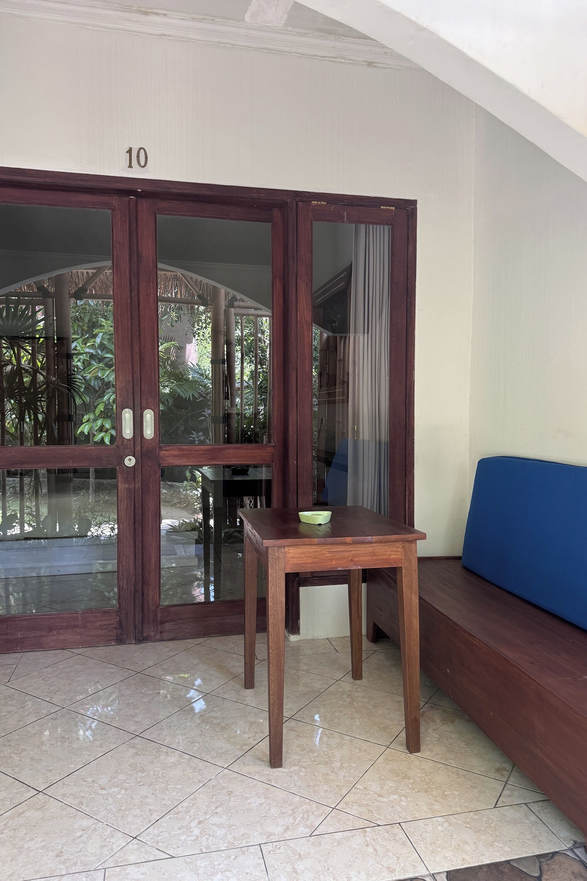 A room with a large wooden door marked with the number 10, a blue sofa, and a small wooden table with a bowl on it.