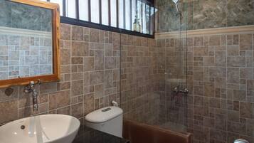 A bathroom with a white sink, a mirror, a toilet, and a shower area.