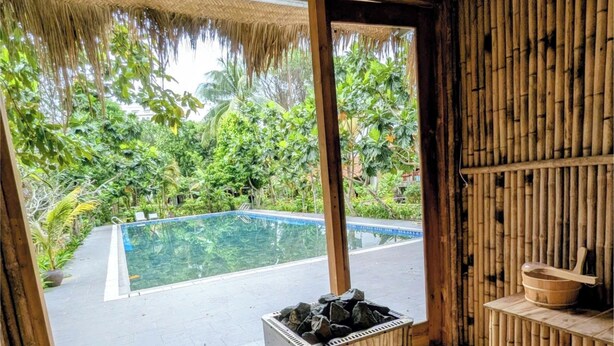 A bamboo sauna with a view of a swimming pool and lush greenery outside. - An Nhien Retreat Phu Quoc (Phu Quoc)