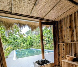 A bamboo sauna with a view of a swimming pool and lush greenery outside. - An Nhien Retreat Phu Quoc (Phu Quoc)
