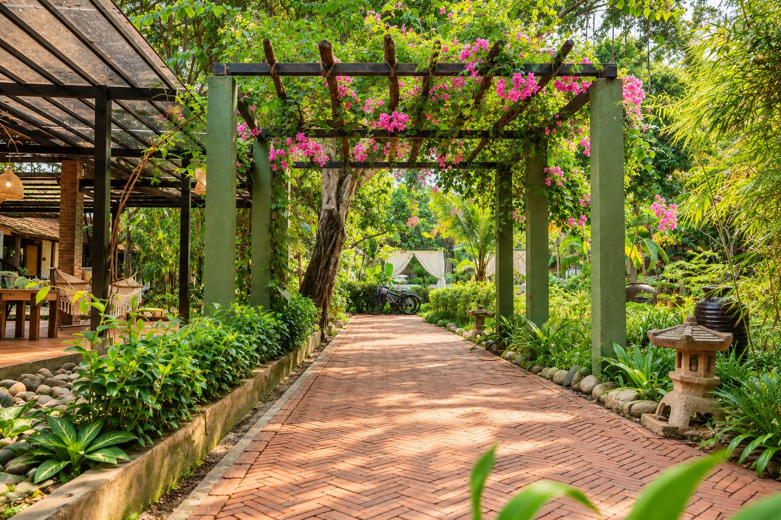 A brick pathway leading through a garden with a pergola covered in pink flowers, surrounded by lush greenery and stone lanterns.
