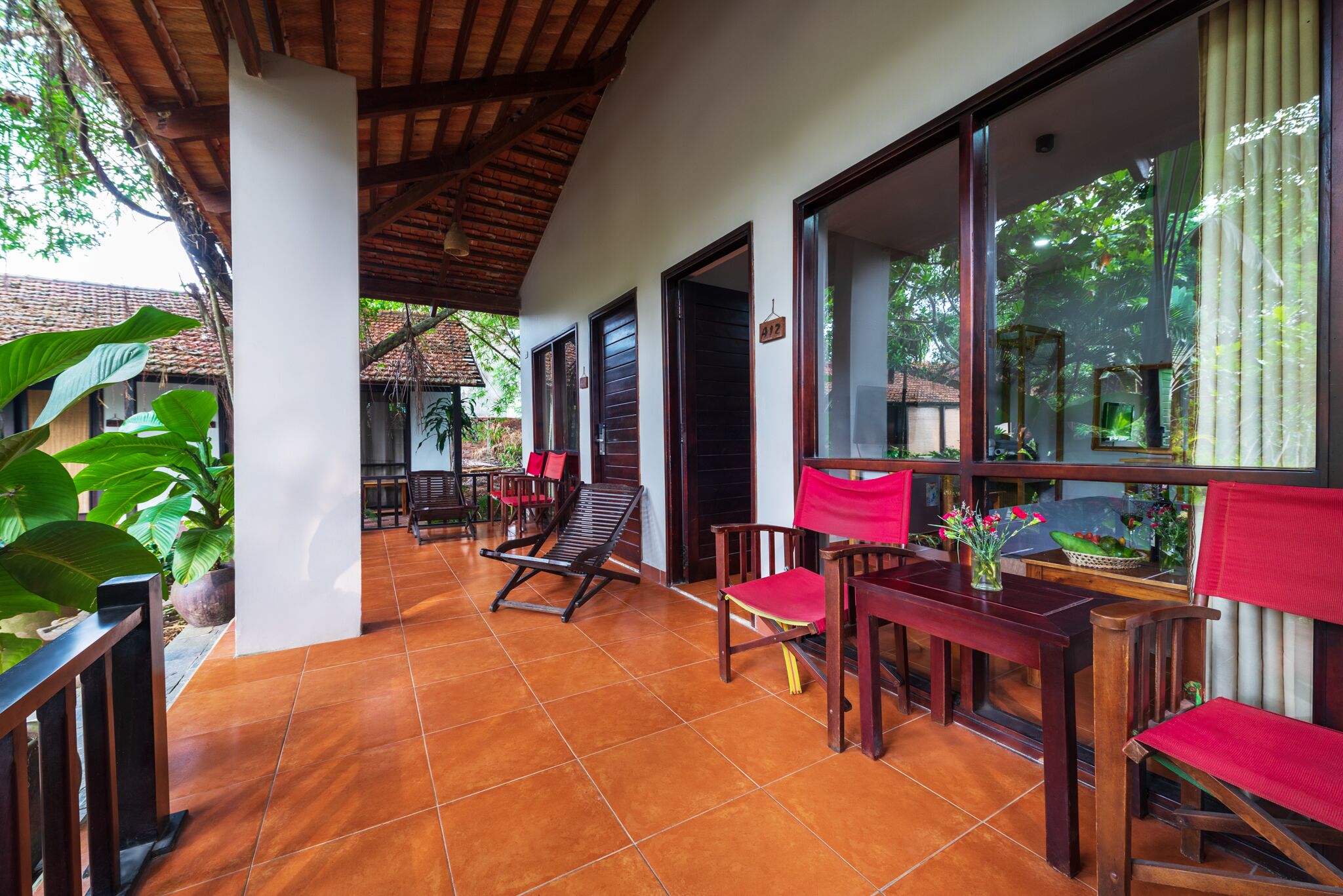 Un patio cubierto con mobiliario de madera y piso de baldosas.