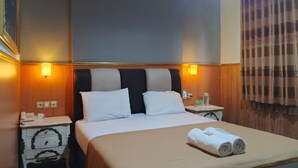 Habitación de hotel con una cama grande, dos mesitas de noche y una lámpara de pared.