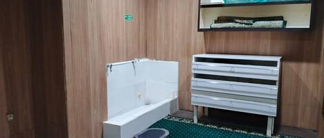 Un baño con bañera, un estante con artículos de aseo y un suelo estampado.