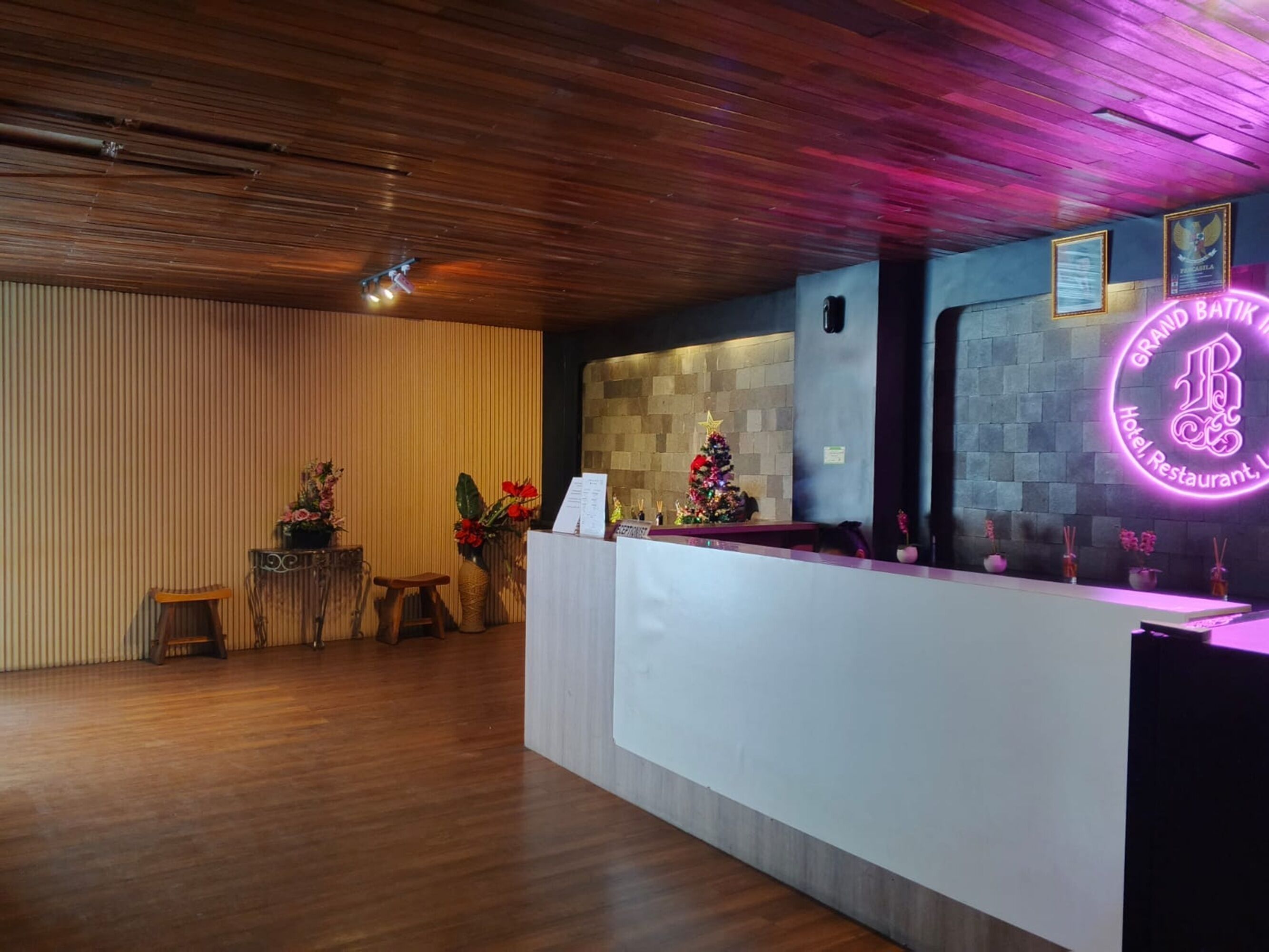 Zona de recepción de hotel con techo de madera, mostrador de recepción y un árbol de Navidad.