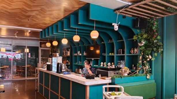 Un interior de restaurante con un mostrador azul turquesa, techo de madera y lámparas colgantes.