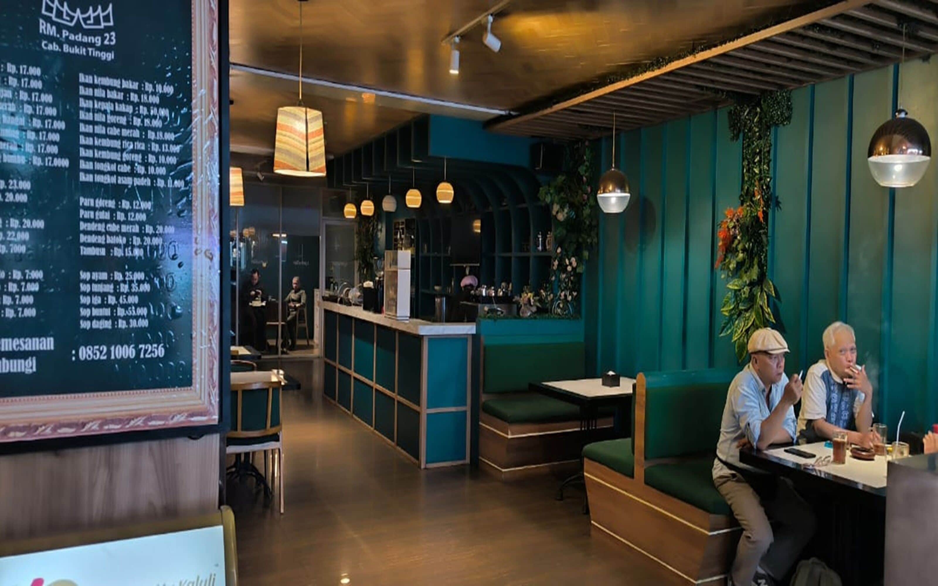 L’intérieur d’un restaurant, avec un tableau affichant le menu, un espace réservé aux clients et un comptoir de bar.