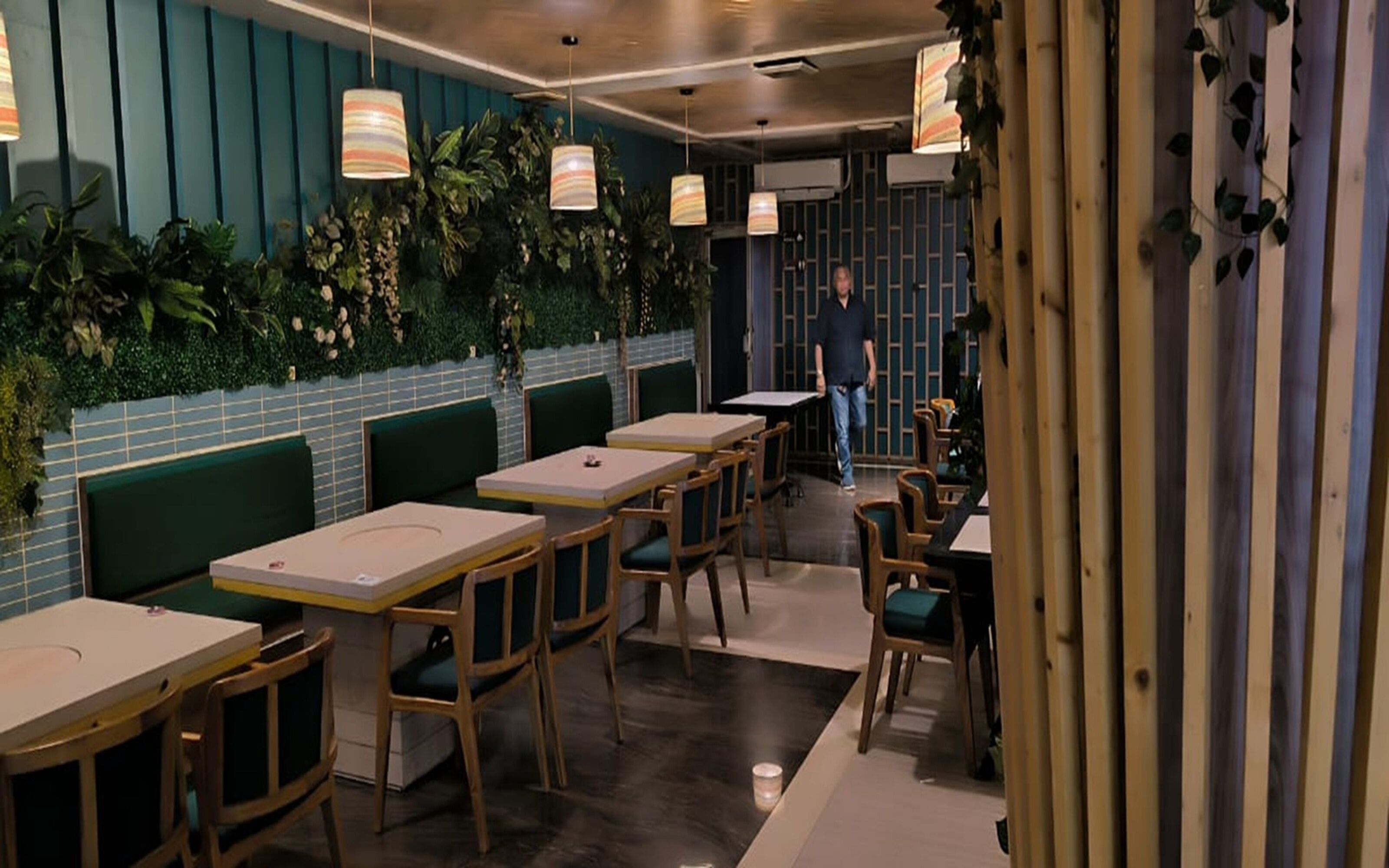 A restaurant interior with booths, wooden tables, and hanging pendant lights.