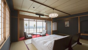 A hotel room with tatami flooring, a bed, a desk, and a view of the ocean. - Wakamatsu Chita Hot Spring Resort  (Minamichita)