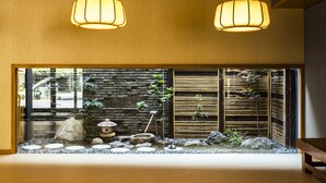 A traditional Japanese interior with a stone wall, bamboo screen, and a small rock garden. - Wakamatsu Chita Hot Spring Resort  (Minamichita)