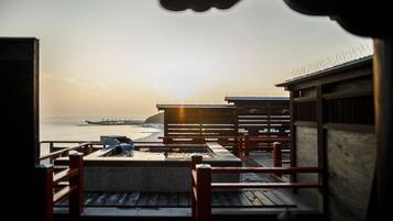 A wooden deck with a view of the ocean and a pier in the distance.