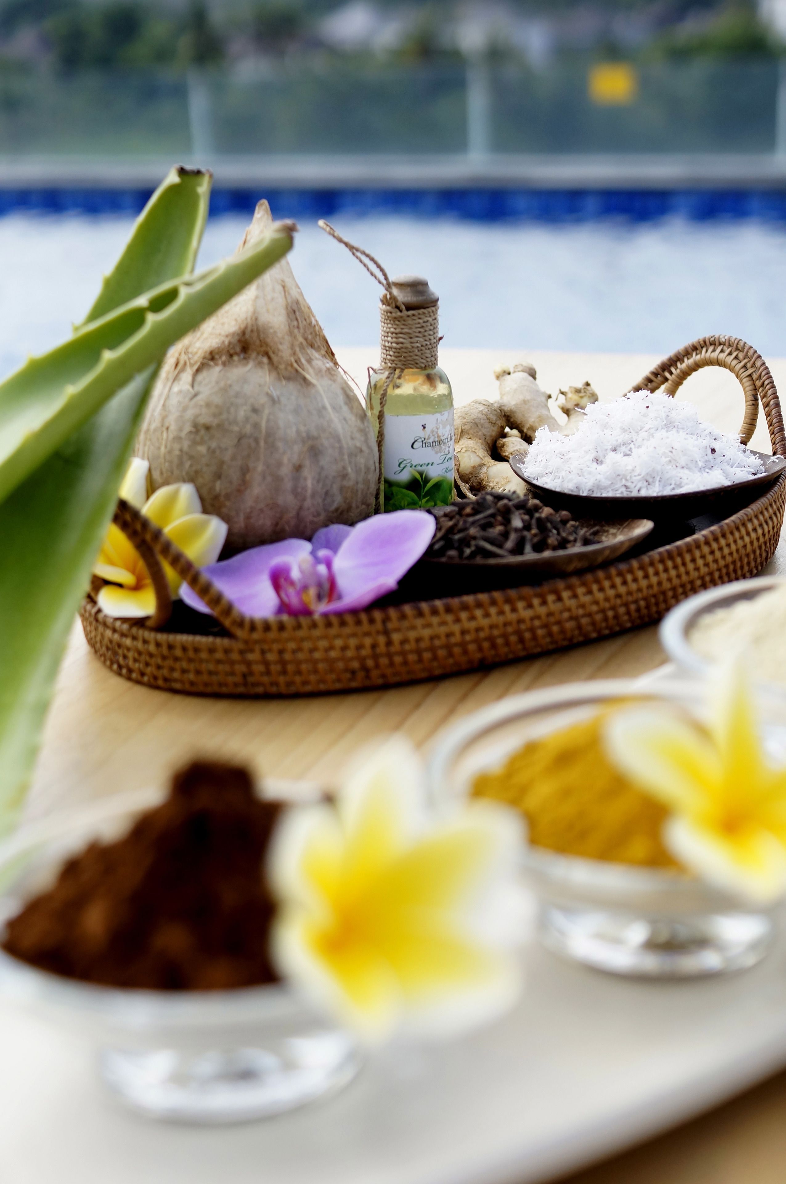 A tray with various spa products including a bottle of oil, dried flowers, and powders.