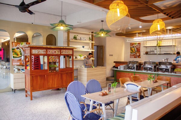 Un interior de restaurante con mobiliario de madera, lámparas de mimbre colgantes y una barra con productos alimenticios.