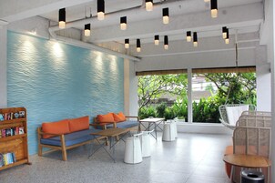 A modern indoor seating area with a blue textured wall, wooden furniture, and a view of greenery outside.
