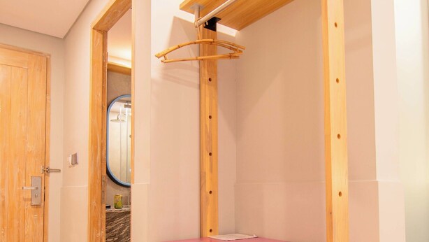 A compact room with a kitchenette, a wooden door, and a mirror. - Koa D'Surfer Hotel (Tibubeneng)