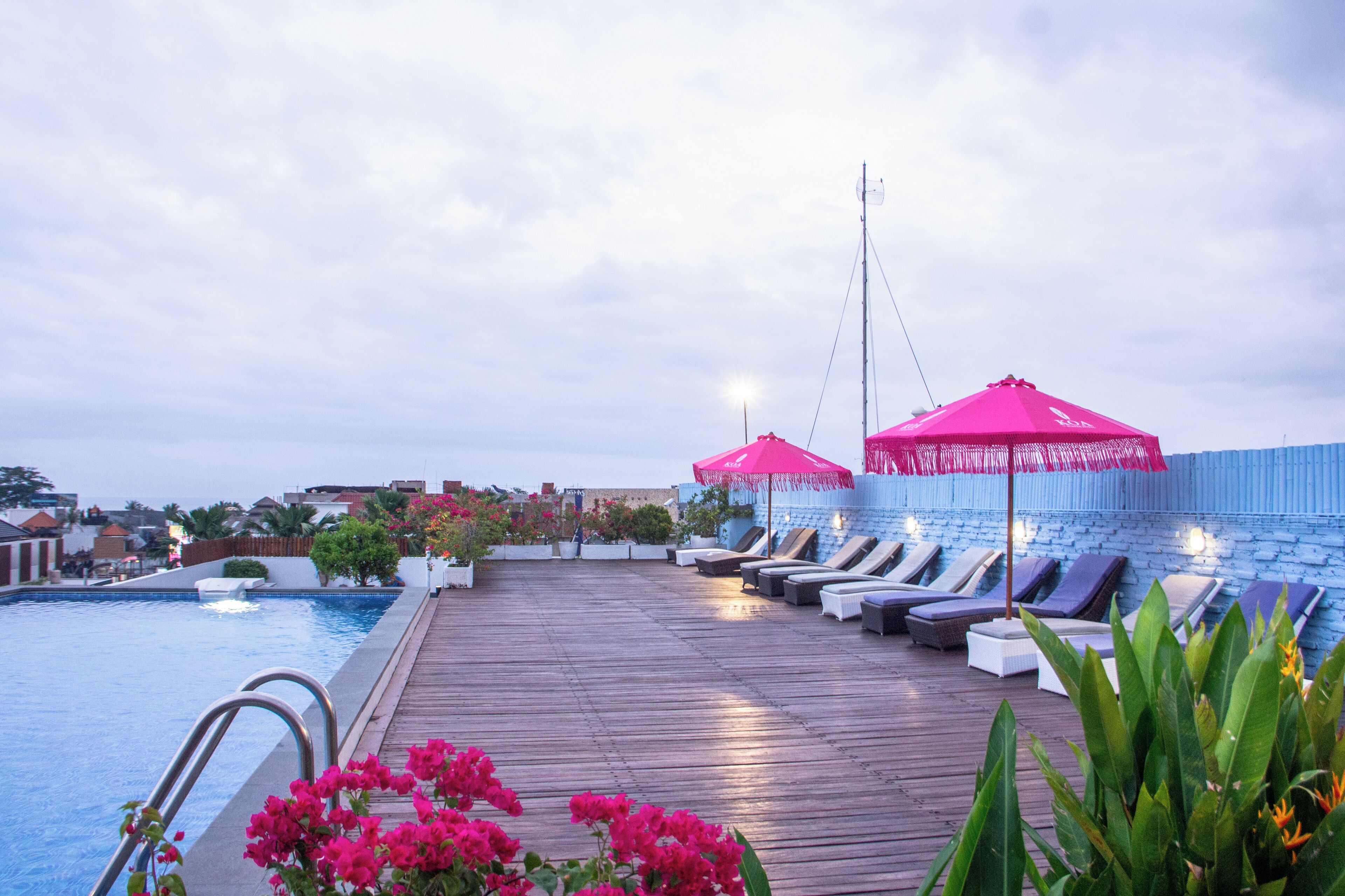 Un espace piscine sur le toit, avec des chaises longues et un parasol rose.
