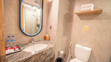 A bathroom with a marble sink, a mirror, a toilet, and a shelf with towels.