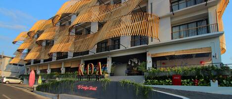 Um hotel com design moderno, apresentando uma fachada singular que lembra bambu e uma placa com a inscrição "KOALA".