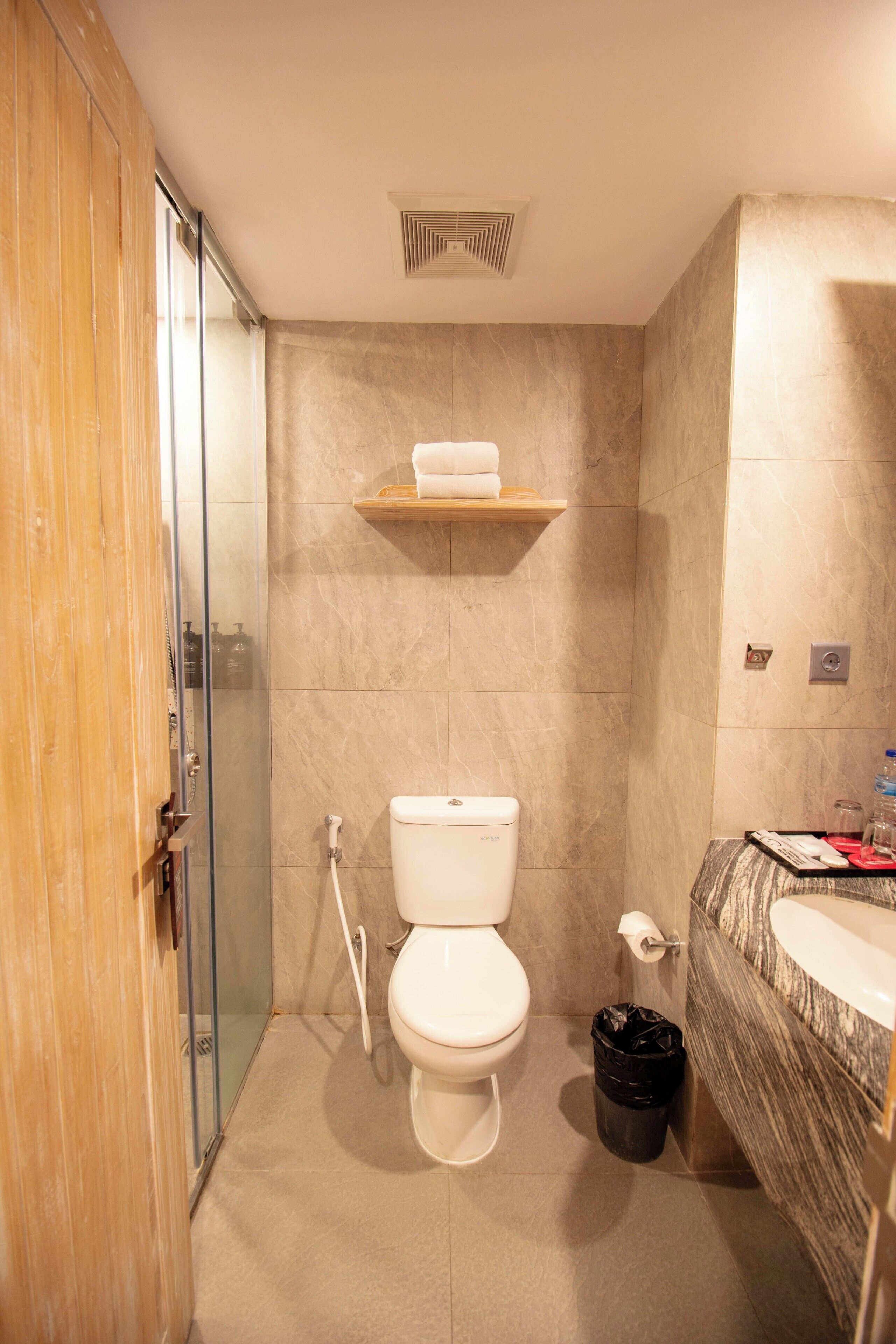 A bathroom with a toilet, shower, and sink.