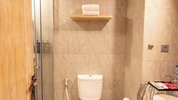 A bathroom with a toilet, shower, and sink.