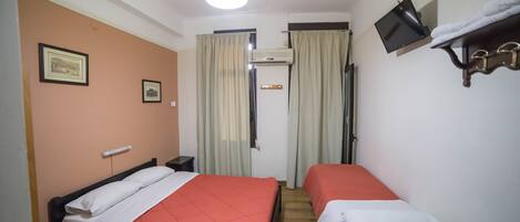 Een hotelkamer met twee bedden, een televisie en een bureau met een afstandsbediening.