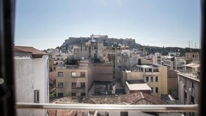 A cityscape with buildings and a hill with a structure on top. - Tempi Hotel (Athens)